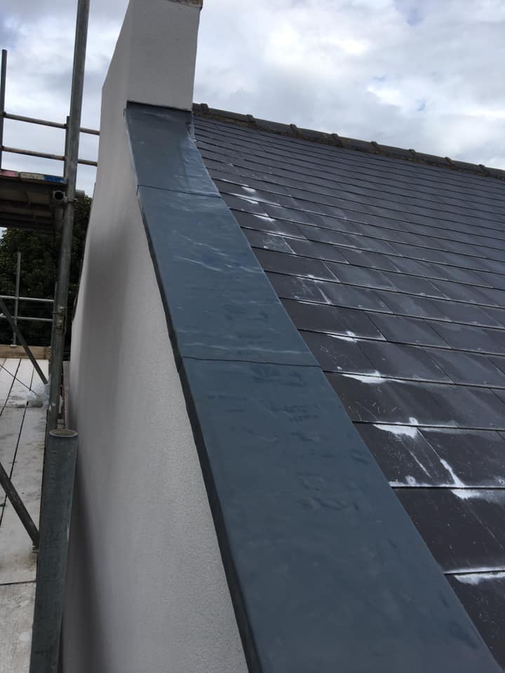 Neatly formed lead flashing beside roof tiles and brickwork